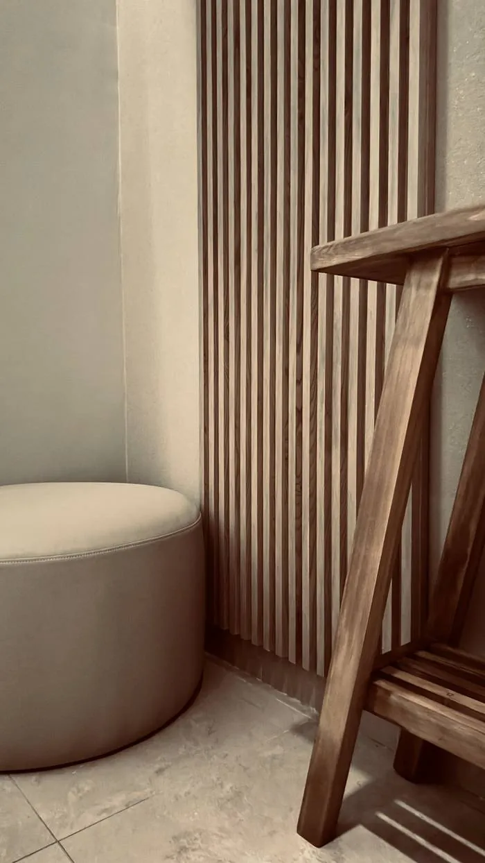 Panel de madera y puf de cuero blanco en cabina privada de Spa Belgrano